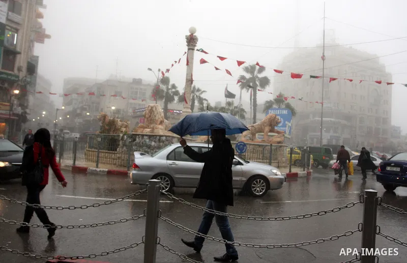 Palestinians walk in a street during the heavy rain and cold winds in the West Bank city of Ramallah on 29 Feb, 2012. Photo by Issam Rimawi