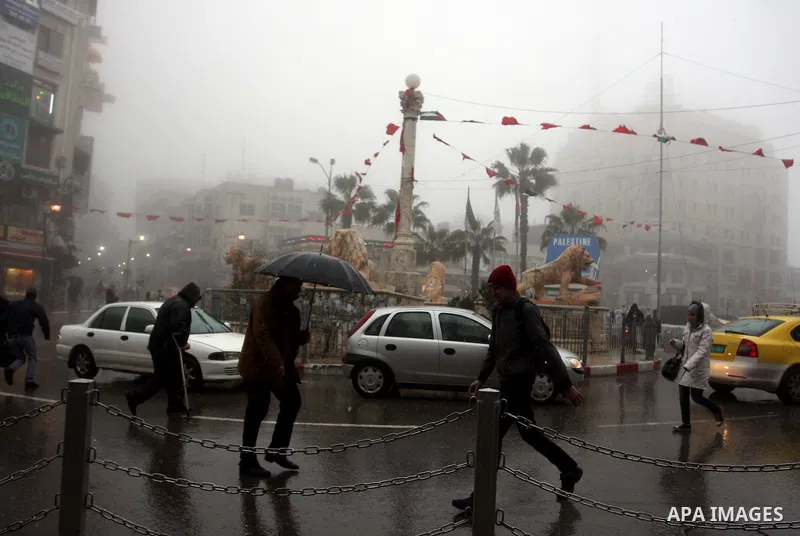 Palestinians walk in a street during the heavy rain and cold winds in the West Bank city of Ramallah on 29 Feb, 2012. Photo by Issam Rimawi