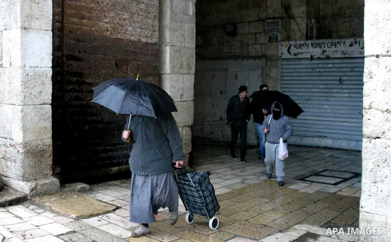 Palestinians walk in a street during the heavy rain and cold winds in Jerusalem's Old City, on Mar. 01, 2012. Photo by Mahfouz Abu Turk
