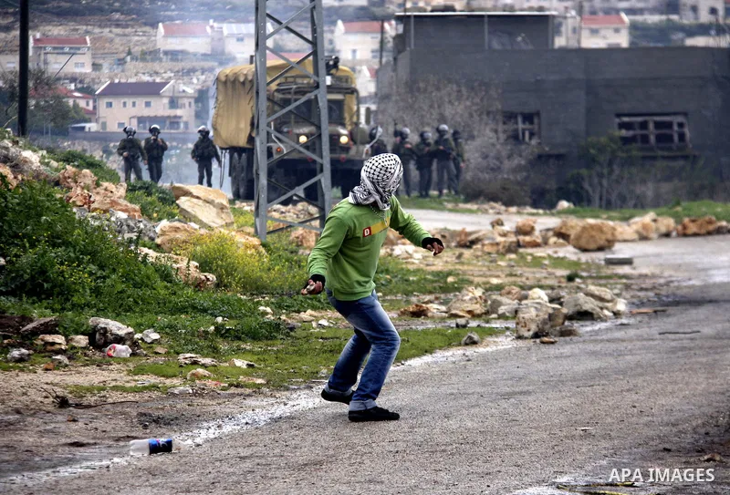 A Palestinian protester throws stones at Israeli soldiers during a demonstration against the expropriation of Palestinian land by Israel in the village of Kfar Qaddum, near the West Bank city of Nablus, on March 2, 2012....