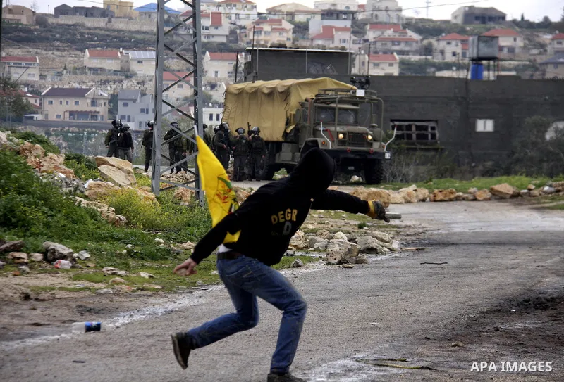 A Palestinian protester throws stones at Israeli soldiers during a demonstration against the expropriation of Palestinian land by Israel in the village of Kfar Qaddum, near the West Bank city of Nablus, on March 2, 2012....