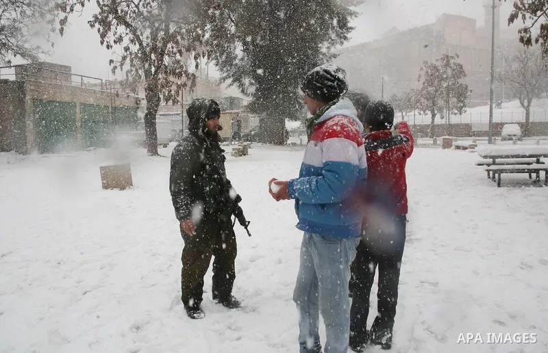 Palestinian youths throw snowballs as they play next to Israeli army position in the West Bank city of Hebron as wintry weather swept through the region on March 2, 2012. Photo by Mamoun Wazwaz