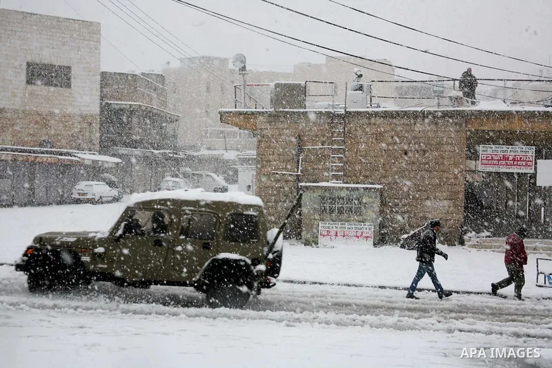 Palestinian youths throw snowballs as they play next to Israeli army position in the West Bank city of Hebron as wintry weather swept through the region on March 2, 2012. Photo by Mamoun Wazwaz