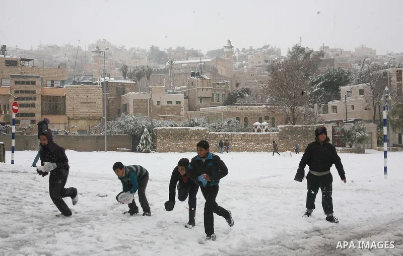 Palestinian youths throw snowballs as they play next to Israeli army position in the West Bank city of Hebron as wintry weather swept through the region on March 2, 2012. Photo by Mamoun Wazwaz