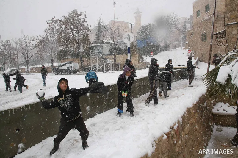 Palestinian youths throw snowballs as they play next to Israeli army position in the West Bank city of Hebron as wintry weather swept through the region on March 2, 2012. Photo by Mamoun Wazwaz