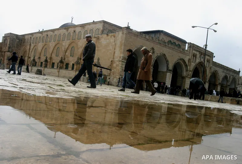 Palestinians walk past rain water in front of the Al-Aqsa mosque after Friday prayers in Jerusalem March 2, 2012. Snow fell in Jerusalem on Friday morning. Local media reported this was the first time in four years that...