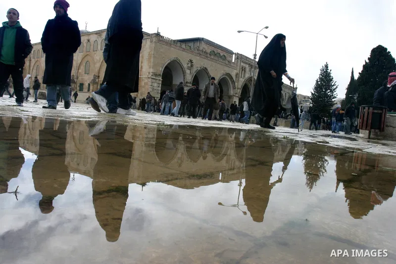 Palestinians walks past rain water in front of the Al-Aqsa mosque in Jerusalem March 2, 2012. Snow fell in Jerusalem on Friday morning. Local media reported this was the first time in four years that snow had fell in Jer...