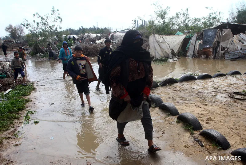 Palestinian Bedouin woman walk through muddy waters after heavy rains which flooded the Al Moghraka area in the central Gaza Strip, 04 March 2012. Photo by Ashraf Amra