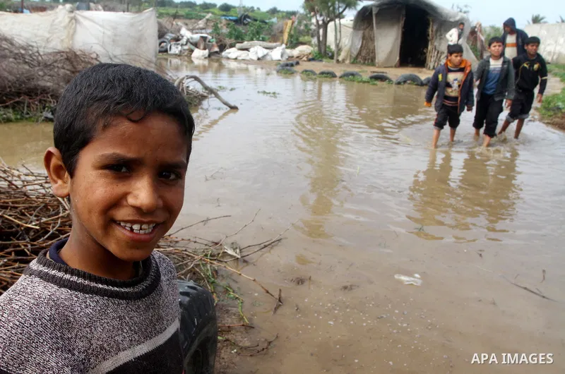 Palestinian Bedouin children walk through muddy waters after heavy rains which flooded the Al Moghraka area in the central Gaza Strip, 04 March 2012. Photo by Ashraf Amra