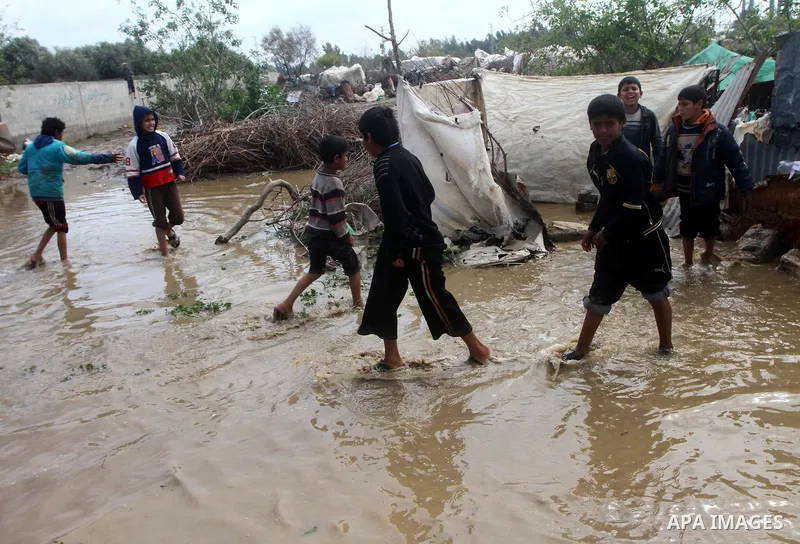 Palestinian Bedouin children walk through muddy waters after heavy rains which flooded the Al Moghraka area in the central Gaza Strip, 04 March 2012. Photo by Ashraf Amra