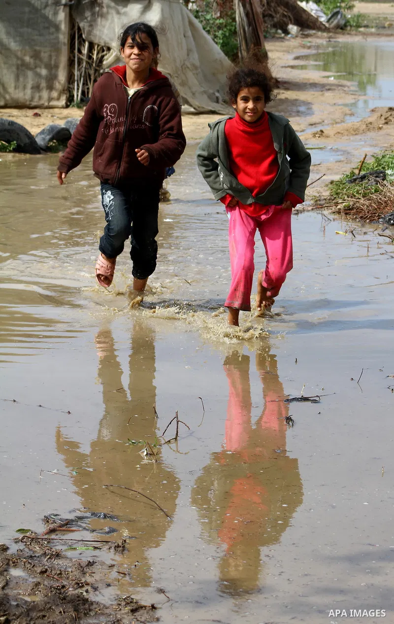 Palestinian Bedouin children walk through muddy waters after heavy rains which flooded the Al Moghraka area in the central Gaza Strip, 04 March 2012. Photo by Ashraf Amra