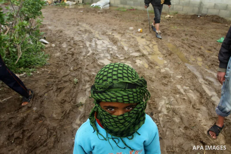 Palestinian Bedouin children walk through muddy waters after heavy rains which flooded the Al Moghraka area in the central Gaza Strip, 04 March 2012. Photo by Ashraf Amra