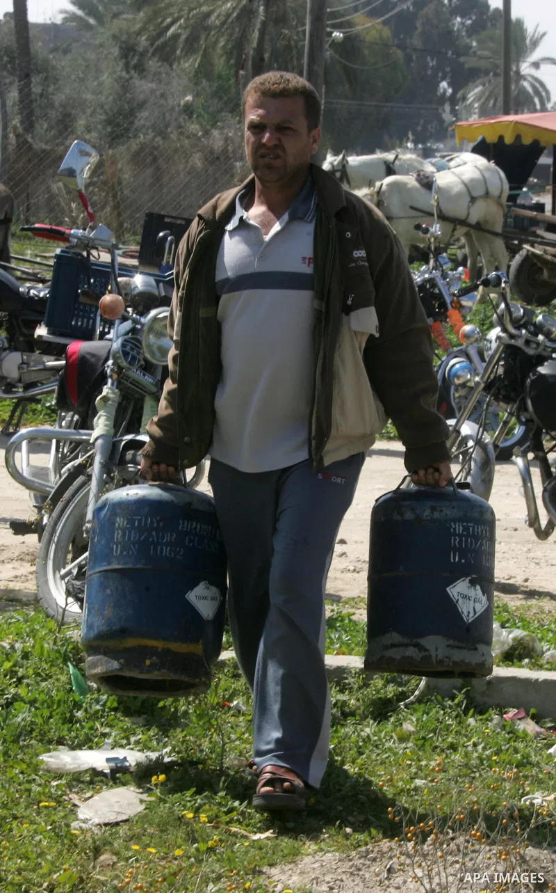 Palestinians wait to fill gas cylinders at a gas filling station in Khan Younis in the southern Gaza Strip March 8, 2012. Photo by Abed Rahim Khatib