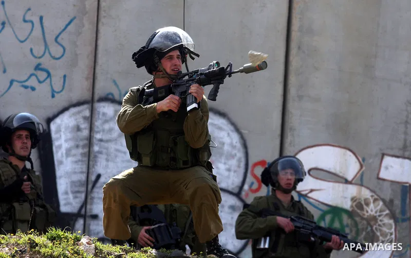 Israeli soldiers standing before the separation wall, protect themselves against teargas during a protest next to the checkpoint of Kalandia, West Bank, 08 March 2012, North of Jerusalem, during a rally to mark the Inter...