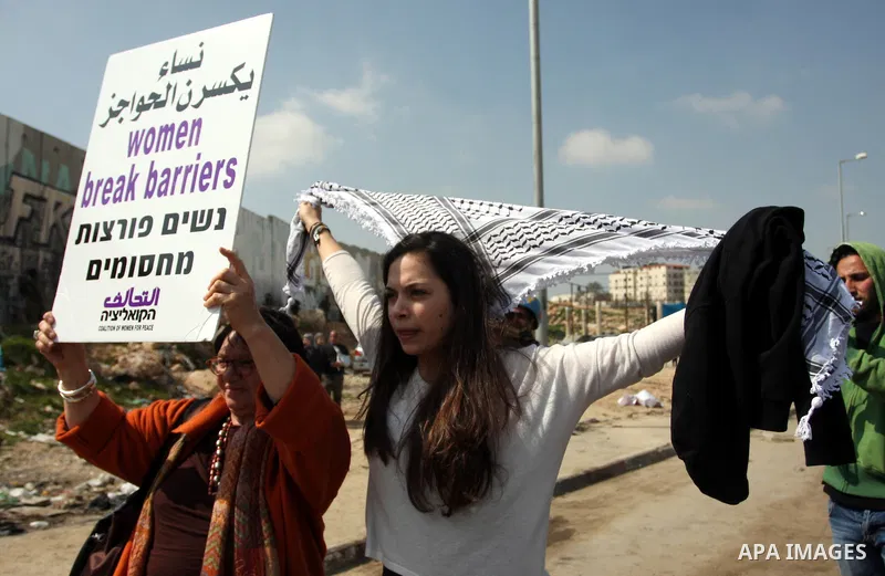 Palestinian woman shout slogans at Israeli soldiers while taking part in a demonstration to remove barriers on Palestinian land, to mark International Women's Day, on March 8, 2012, in the West Bank town of Qalandia. Pho...