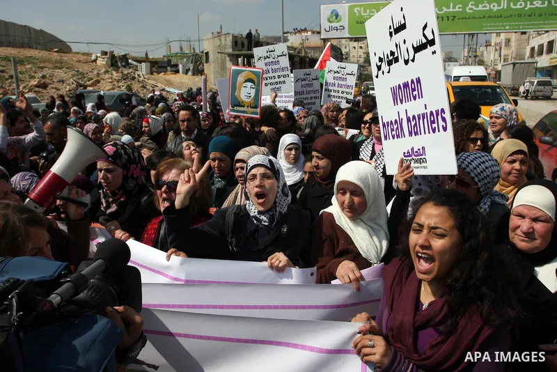 Palestinian woman shout slogans at Israeli soldiers while taking part in a demonstration to remove barriers on Palestinian land, to mark International Women's Day, on March 8, 2012, in the West Bank town of Qalandia. Pho...