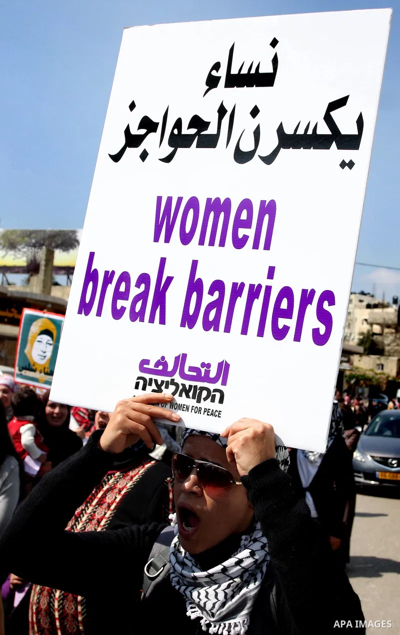 Palestinian woman shout slogans at Israeli soldiers while taking part in a demonstration to remove barriers on Palestinian land, to mark International Women's Day, on March 8, 2012, in the West Bank town of Qalandia. Pho...