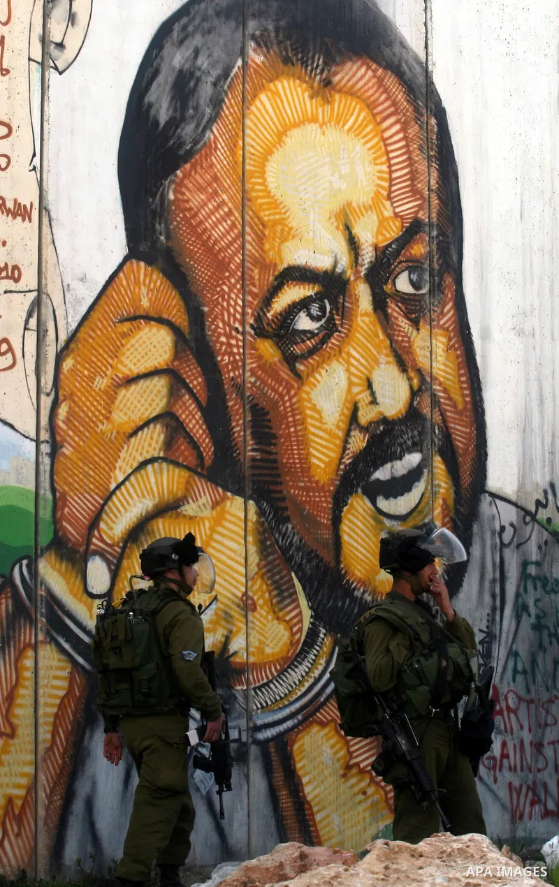 Israeli soldiers standing before the separation wall, protect themselves against teargas during a protest next to the checkpoint of Kalandia, West Bank, 08 March 2012, North of Jerusalem, during a rally to mark the Inter...