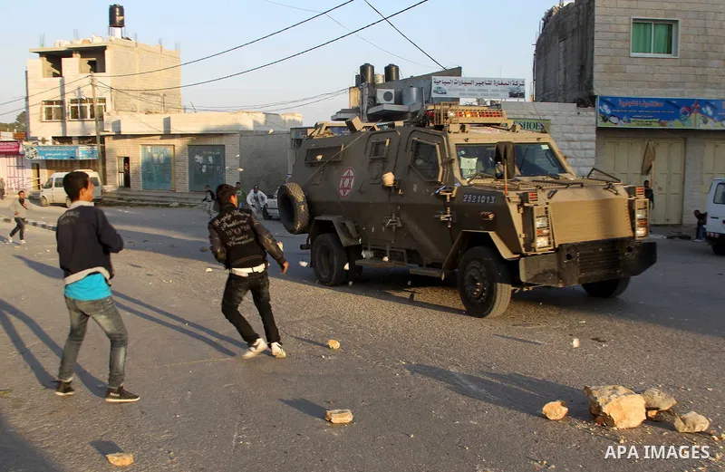 Palestinians throw stones at an Israeli military vehicle in the main street of the villlage of Yatta, south of the West Bank town of Hebron, after an Israeli soldier shot and killed a 17-year old Palestinian, Zakarya Abu...