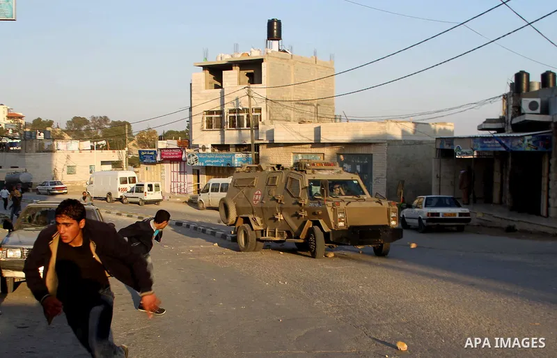 Palestinians throw stones at an Israeli military vehicle in the main street of the villlage of Yatta, south of the West Bank town of Hebron, after an Israeli soldier shot and killed a 17-year old Palestinian, Zakarya Abu...