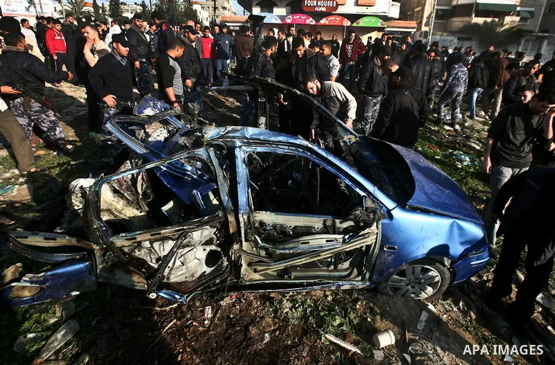 Palestinians look at the remains of a vehicle after it exploded in Gaza City March 9, 2012. Israel killed the leader of a Palestinian militant faction on Friday in a targeted attack on the car in the Gaza Strip, an Israe...