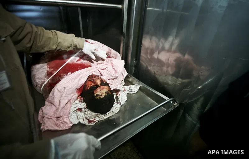 Palestinians look at the body of Mahmud Halani, a member of the Popular Resistance Committees militant group, after he was killed along with the General Secretary of PRC, Zohair al-Qaisi, in an Israeli air strike that ta...
