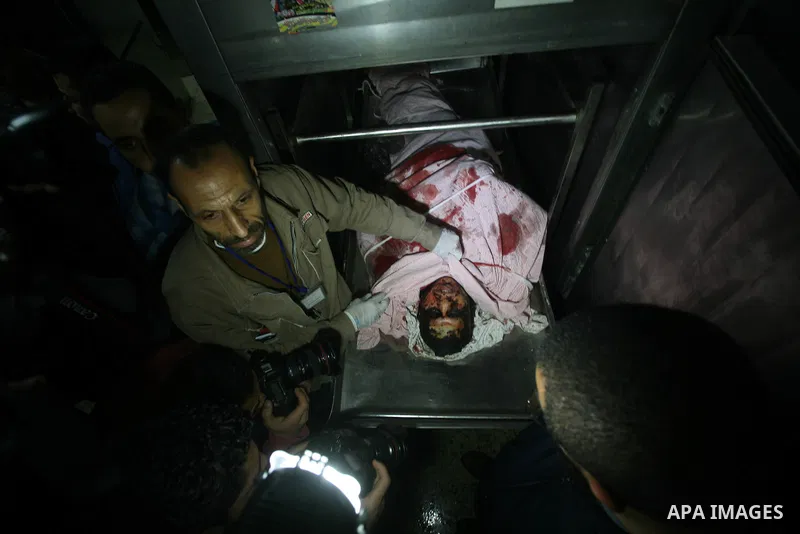 Palestinians look at the body of Mahmud Halani, a member of the Popular Resistance Committees militant group, after he was killed along with the General Secretary of PRC, Zohair al-Qaisi, in an Israeli air strike that ta...