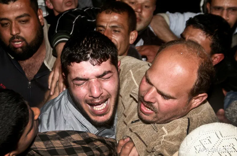 Palestinians mourn in a hospital over the body of one of two militants of the Al Quds Brigades, the military arm of Islamic Jihad, after they were killed in a second Israeli air strike in Gaza City on March 9, 2012, brin...