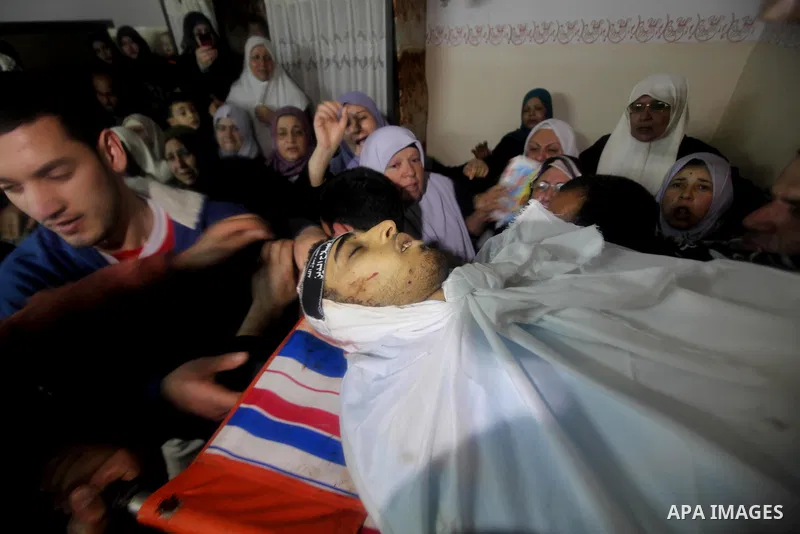 Palestinian mourners carry the body of 22-year-old Ahmed Salim, one of the Nasser Salahaldin Brigades militants who was killed in an Israeli air strike, grieves during his funeral in Gaza City, on March 11, 2012. Photo b...