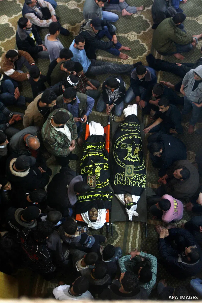 Palestinians mourn beside the bodies of two Islamic Jihad militants Mohammed Daher, left, and Bassam Al Ejla killed in an Israeli air strike in Gaza Tuesday, during their funeral in Gaza City, Tuesday, March 13, 2012 . I...