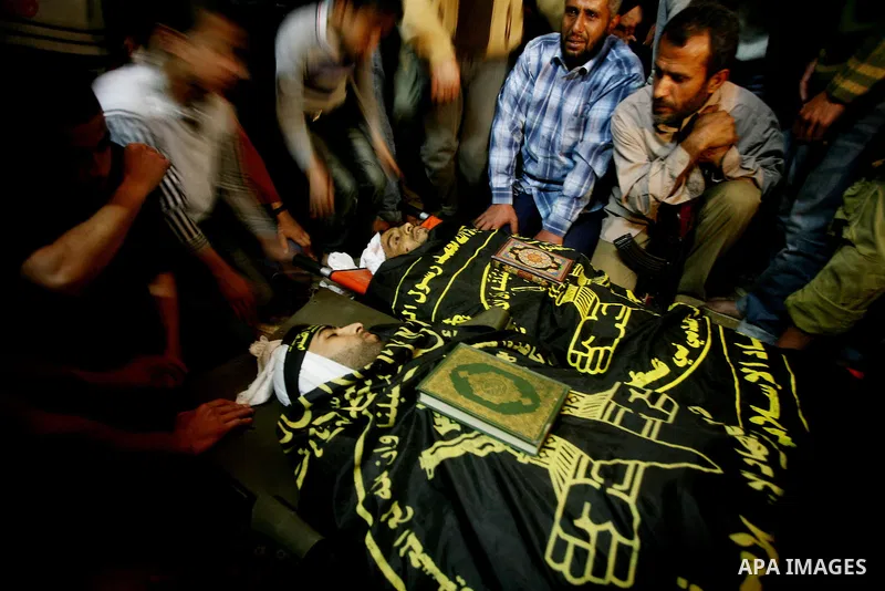 Palestinians mourn beside the bodies of two Islamic Jihad militants Mohammed Daher, left, and Bassam Al Ejla killed in an Israeli air strike in Gaza Tuesday, during their funeral in Gaza City, Tuesday, March 13, 2012 . I...