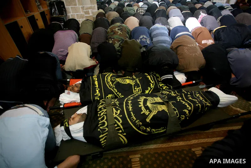 Palestinians pray on the bodies of two Islamic Jihad militants Mohammed Daher, left, and Bassam Al Ejla killed in an Israeli air strike in Gaza Tuesday, during their funeral in Gaza City, Tuesday, March 13, 2012 . Israel...