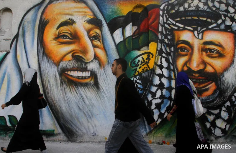 palestinians walk near of the mural of late Palestinian leader Yasser Arafat and late Hamas leader Sheikh Ahmed Yassin , in Gaza City on March 14, 2012. Photo by Ashraf Amra