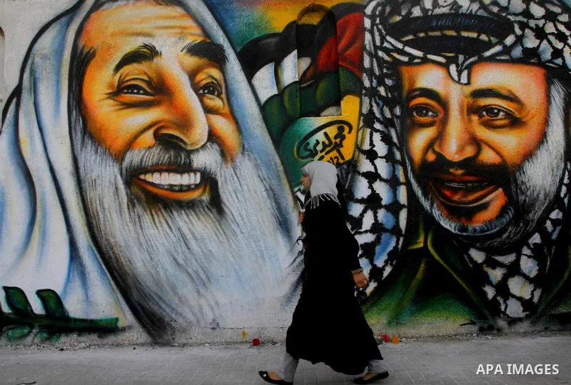 palestinians walk near of the mural of late Palestinian leader Yasser Arafat and late Hamas leader Sheikh Ahmed Yassin , in Gaza City on March 14, 2012. Photo by Ashraf Amra