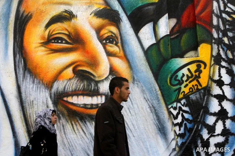 palestinians walk near of the mural of late Palestinian leader Yasser Arafat and late Hamas leader Sheikh Ahmed Yassin , in Gaza City on March 14, 2012. Photo by Ashraf Amra