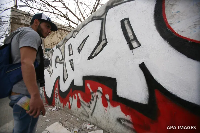 Palestinian students paint graffiti depicting word "Gaza" to show their support for the Gaza Strip and against Israeli air strikes, in the West Bank city of Hebron, on March 15, 2012. Photo by Mamoun Wazwaz.