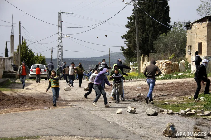 Palestinian youths hurl stones at Israeli security forces ,during a protest in the village of Kufr Qaddum near the Israeli settlement of Kdumim, in the northern West Bank, Friday,March 16, 2012. Photo by Wagdi Eshtayah