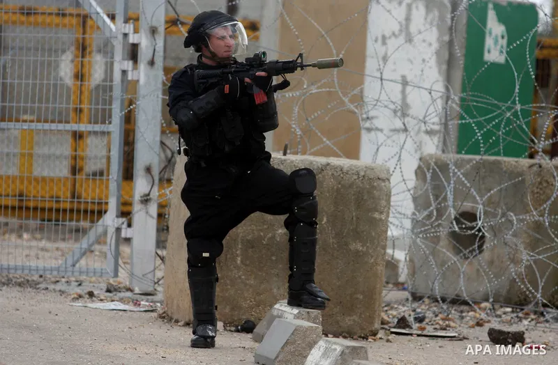 An Israeli soldier launches a tear gas grenade during a demonstration at the entrance to Ofer Prison near Ramallah in the Occupied West Bank to support female prisoner Hanaa al-Shalabi (portrait) who was freed in a priso...
