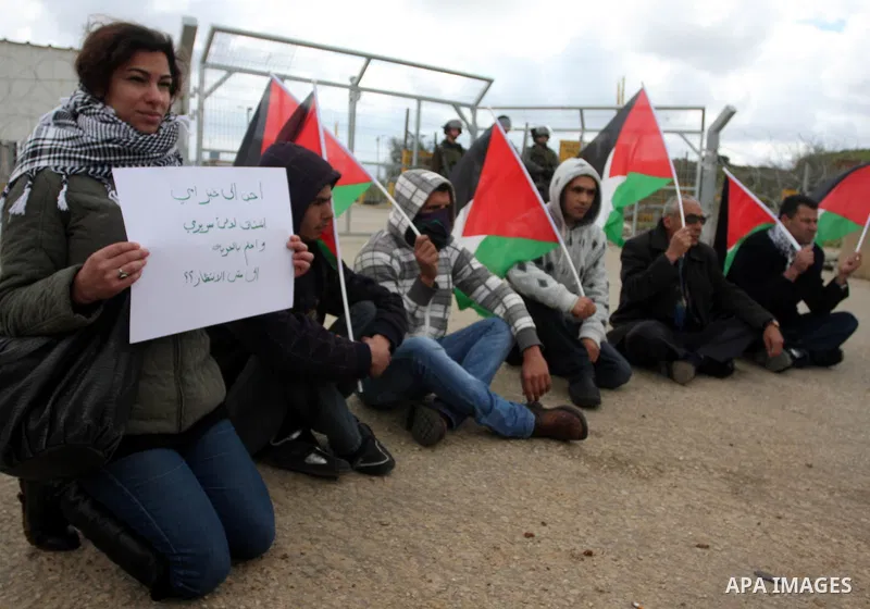 Palestinian protestors attach Palestinian flags on the gates of the Ofer Prison near Ramallah in the Occupied West Bank during a sit-in on March 27, 2012, organized by dozens of youths outside the jail to support impriso...