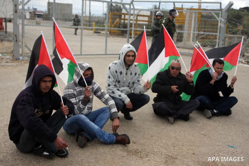 Palestinian protestors attach Palestinian flags on the gates of the Ofer Prison near Ramallah in the Occupied West Bank during a sit-in on March 27, 2012, organized by dozens of youths outside the jail to support impriso...