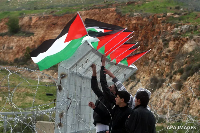 Palestinian protestors attach Palestinian flags on the gates of the Ofer Prison near Ramallah in the Occupied West Bank during a sit-in on March 27, 2012, organized by dozens of youths outside the jail to support impriso...