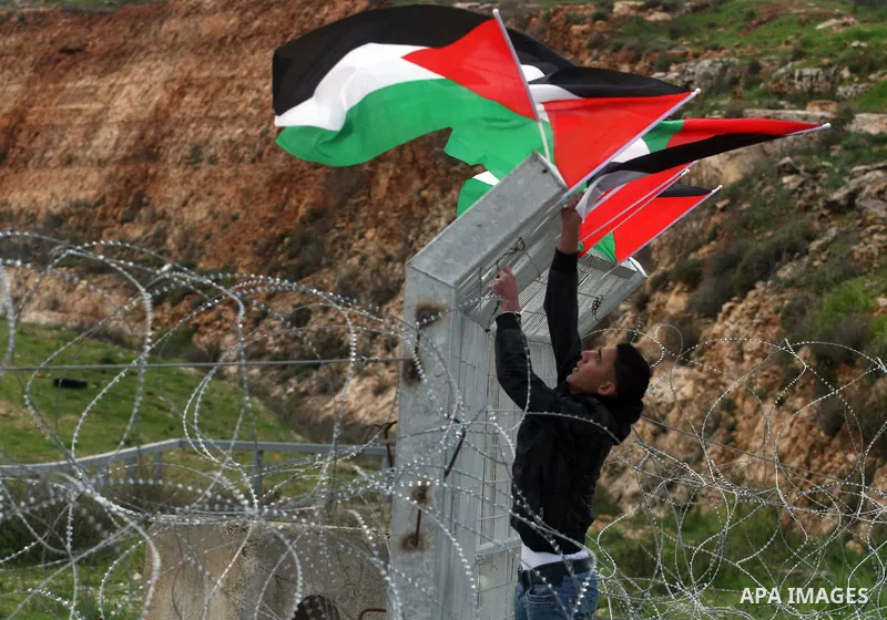 Palestinian protestors attach Palestinian flags on the gates of the Ofer Prison near Ramallah in the Occupied West Bank during a sit-in on March 27, 2012, organized by dozens of youths outside the jail to support impriso...