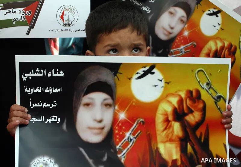 Palestinian children hold portraits of jailed compatriot Hana Shalabi, a female Palestinian prisoner jailed in Israel who has been on hunger strike for 26 days, outside the Red Cross building in the West Bank city of Heb...