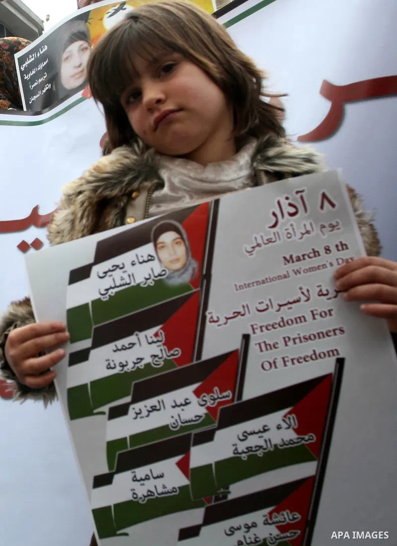 Palestinian children hold portraits of jailed compatriot Hana Shalabi, a female Palestinian prisoner jailed in Israel who has been on hunger strike for 26 days, outside the Red Cross building in the West Bank city of Heb...