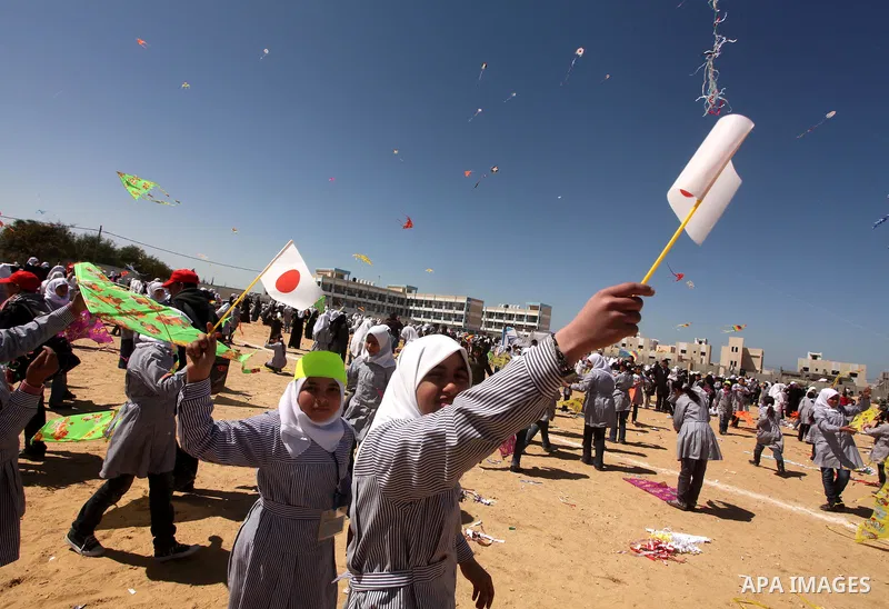 Palestinian children fly kites to show their solidarity with the Japanese people near a Japanese-funded housing project in Khan Younis in the southern Gaza Strip March 18, 2012. The event was organized by the United Nati...