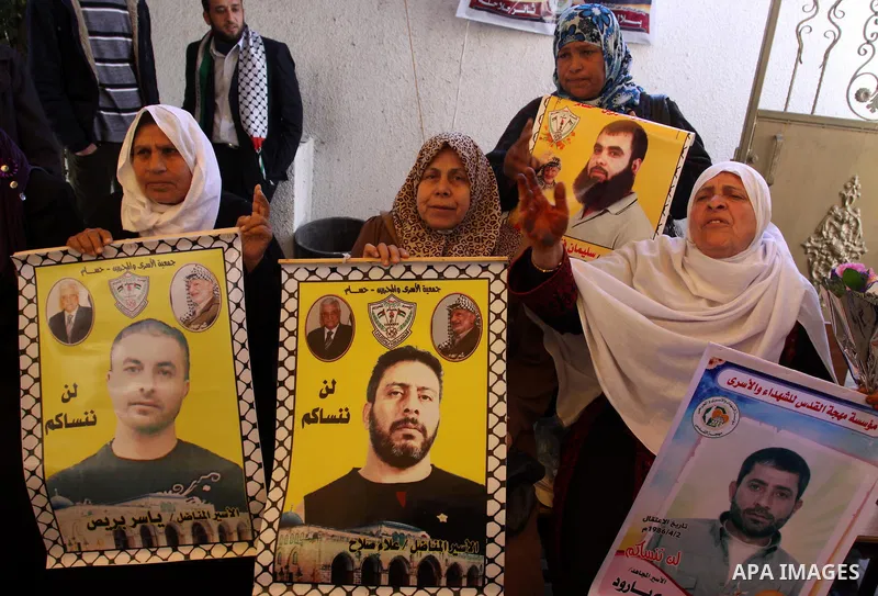 Palestinian women hold an image of the prisoners , as she and other protest calling for the release of Palestinian prisoners being held in Israeli jails inside the grounds of the Red Cross headquarters in Gaza City on Ma...