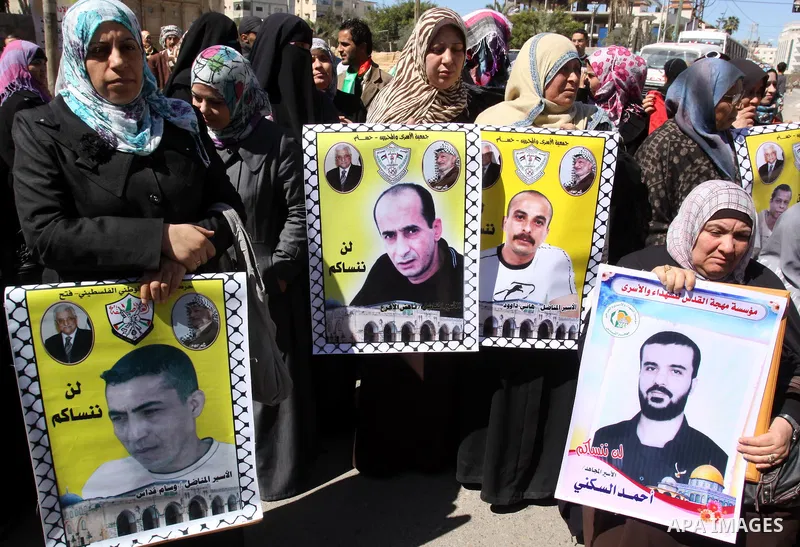 Palestinian women hold an image of the prisoners , as she and other protest calling for the release of Palestinian prisoners being held in Israeli jails inside the grounds of the Red Cross headquarters in Gaza City on Ma...