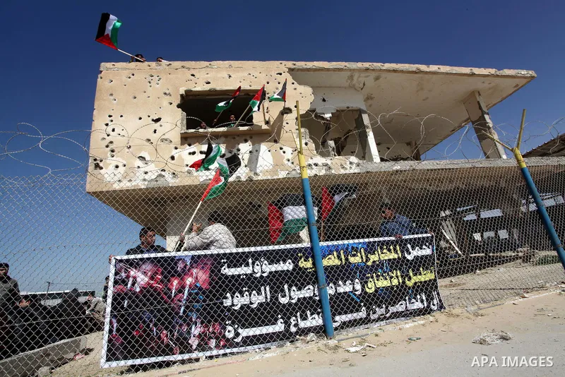 Palestinian demonstrators wave national flags during a protest in the Rafah border crossing with Egypt on March 19, 2012, demanding Egypt provide the Gaza Strip with electricity and fuel. The Palestinian energy authority...