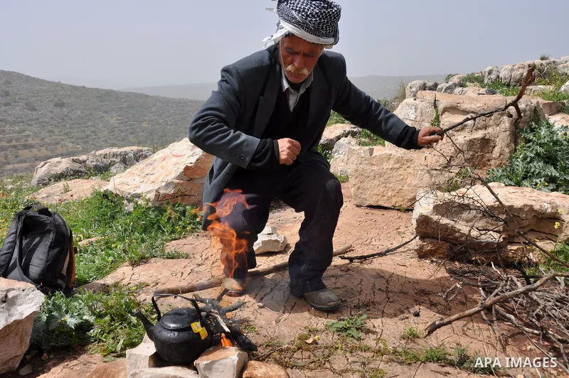 Palestinian shepherd Abu Jaafar makes a tea by a fire in Biet Leed village near the West Bank city of Tulkarem, 20 March 2012. Photo by Nedal Eshtayah