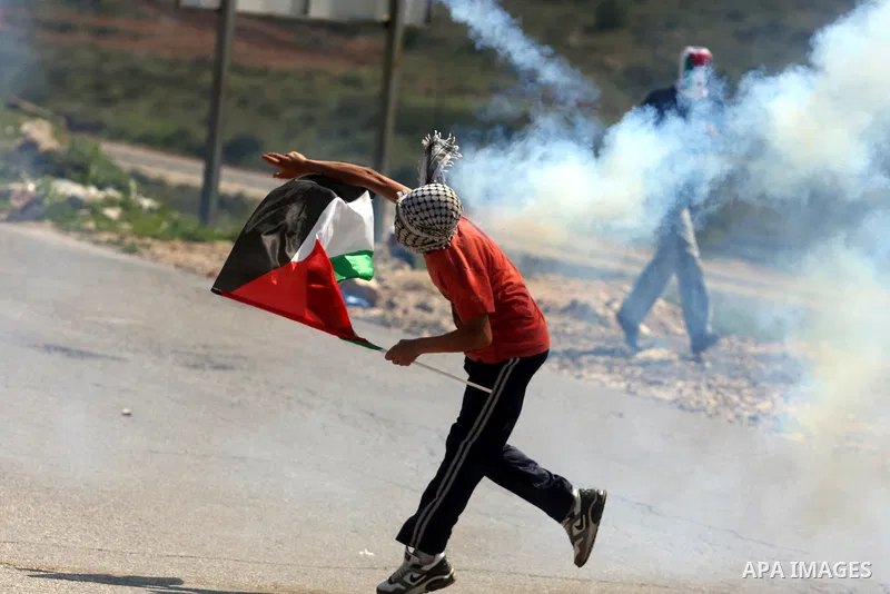 A Palestinian demonstrator returns a tear gas canister towards Israeli soldiers during a protest against the expansion of the nearby Jewish settlement of Halamish in the West Bank village of Nabi Saleh near Ramallah, Fri...